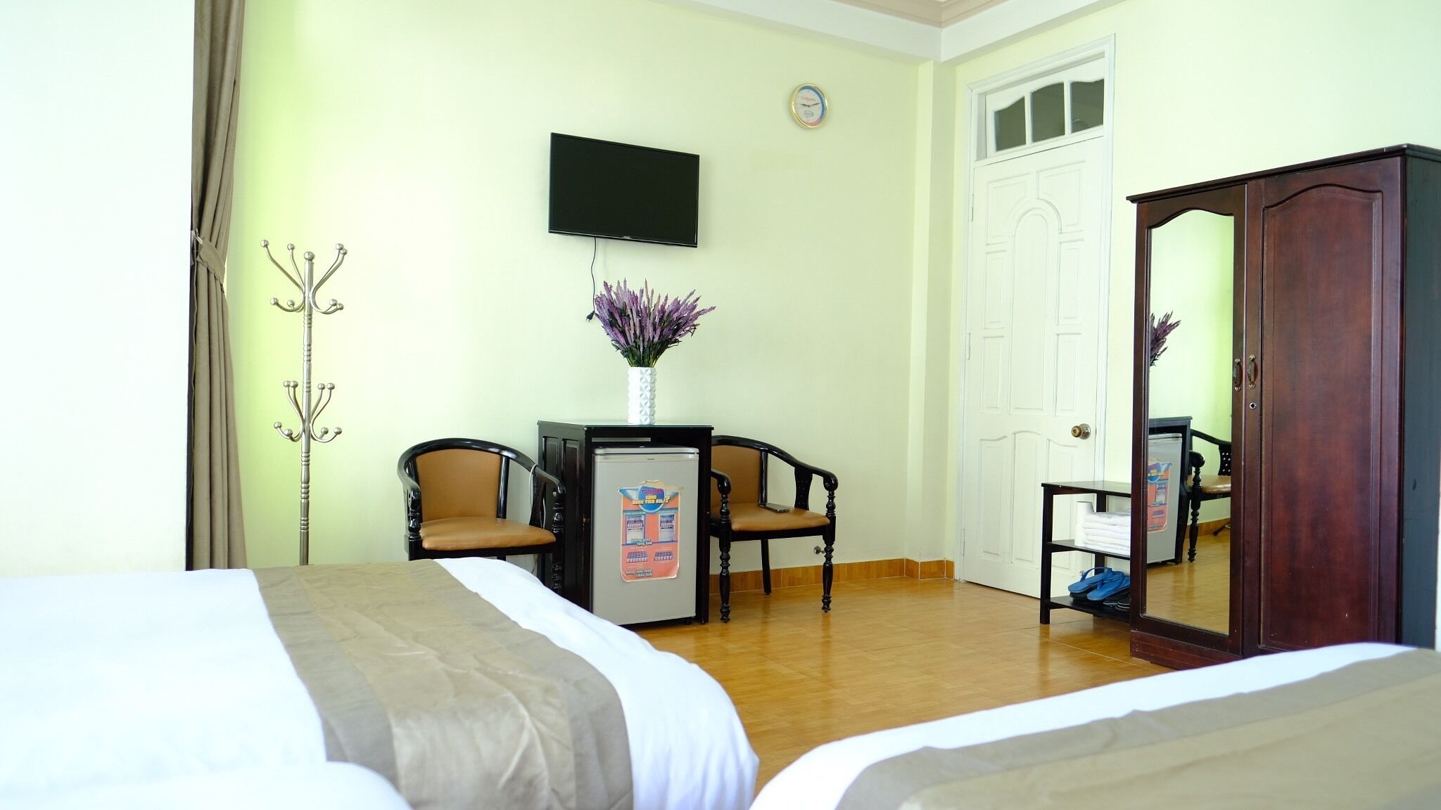 A hotel room with two beds, a desk with a computer, a television, a wardrobe, and a mirror.