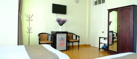 A hotel room with two beds, a desk with a computer, a television, a wardrobe, and a mirror.