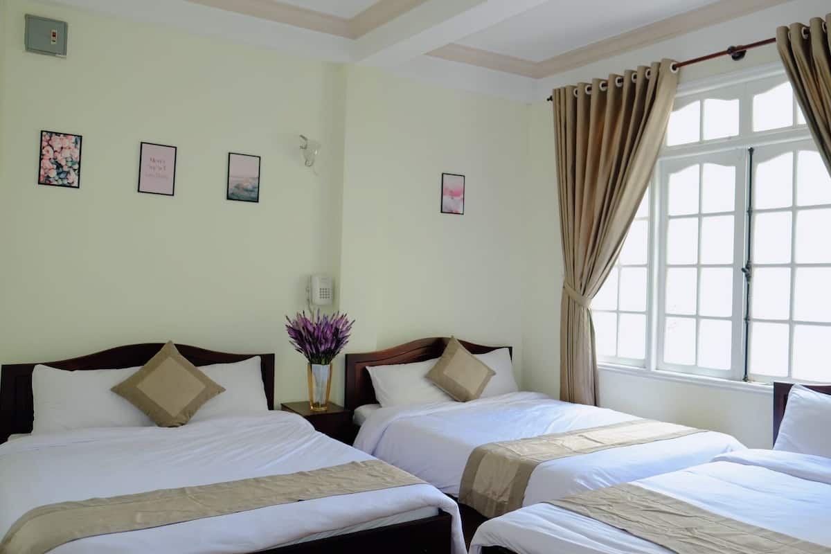 Habitación de hotel con dos camas individuales, cortinas color crema, una ventana con vistas y una obra de arte en la pared.