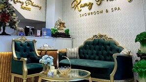 A luxurious showroom and spa area with a green sofa, gold-trimmed chairs, and a crystal chandelier. - Kamy Phuong House and Spa (Xuan Huong - Da Lat)