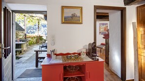 A cozy interior with a wooden ceiling, a red counter with a coffee machine, and a painting on the wall.