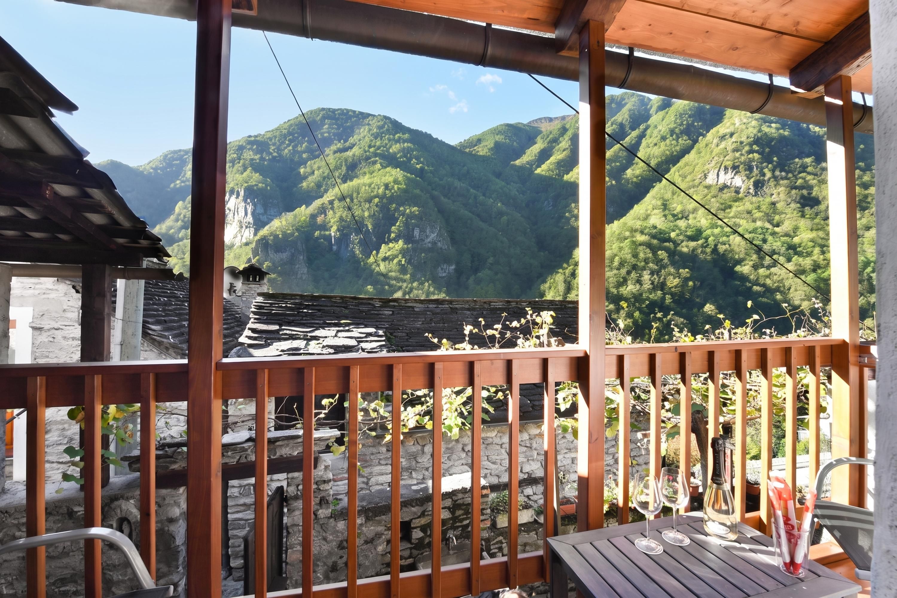 Un balcon en bois avec un mur en pierre, donnant sur un paysage montagneux.
