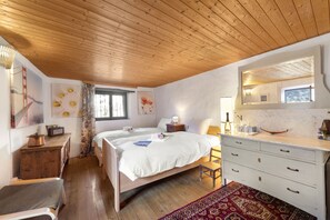 A bedroom with two beds, a wooden ceiling, a large mirror, a dresser, and a window with curtains. - Casa Carla 2 Stone House with Balcony, Vogorno, Switzerland (Vogorno)
