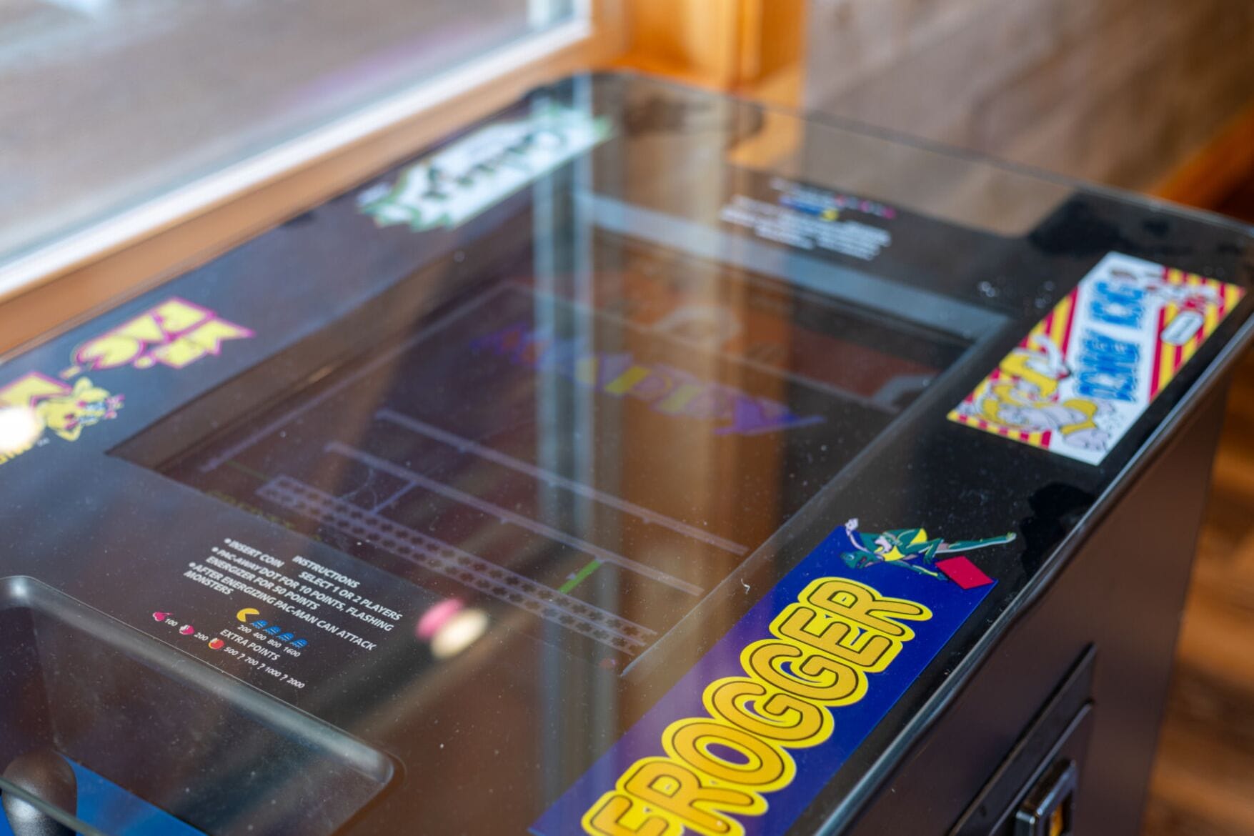 Une machine à pinces ornée d’un autocollant représentant le jeu « Frogger », et dont les instructions sont visibles sur le panneau de verre.
