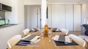 A modern dining area with a wooden table set for six, a bottle of whiskey, and glasses.