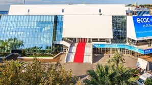 A modern building with a glass facade, a red entrance ramp, and signage for an event from 21-25 September.