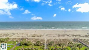 A beach with a clear sky, calm sea, and a view of the ocean. - Direct Oceanfront Two Bedroom Condo (Myrtle Beach)