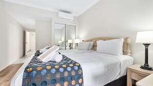 Une chambre d’hôtel avec un lit, des lampes de chevet, un miroir et une petite table avec une lampe.