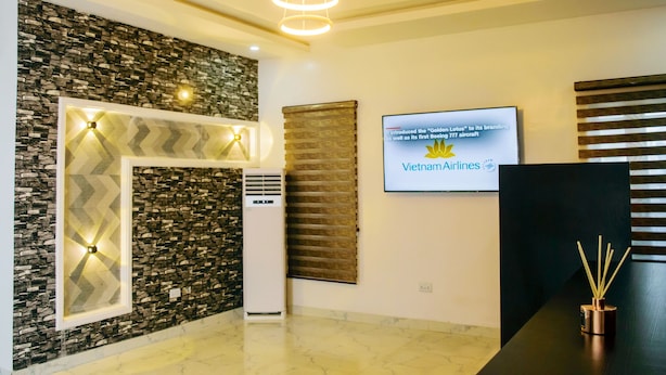 Un área de recepción moderna con una pared de piedra, una pantalla grande mostrando el logotipo de Vietnam Airlines y un mostrador de recepción negro.