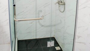 Un box de ducha con paredes de vidrio, un cabezal de ducha manual y un grifo instalado en la pared.