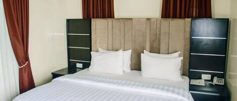 A hotel room with a bed, two nightstands, a telephone, and curtains.