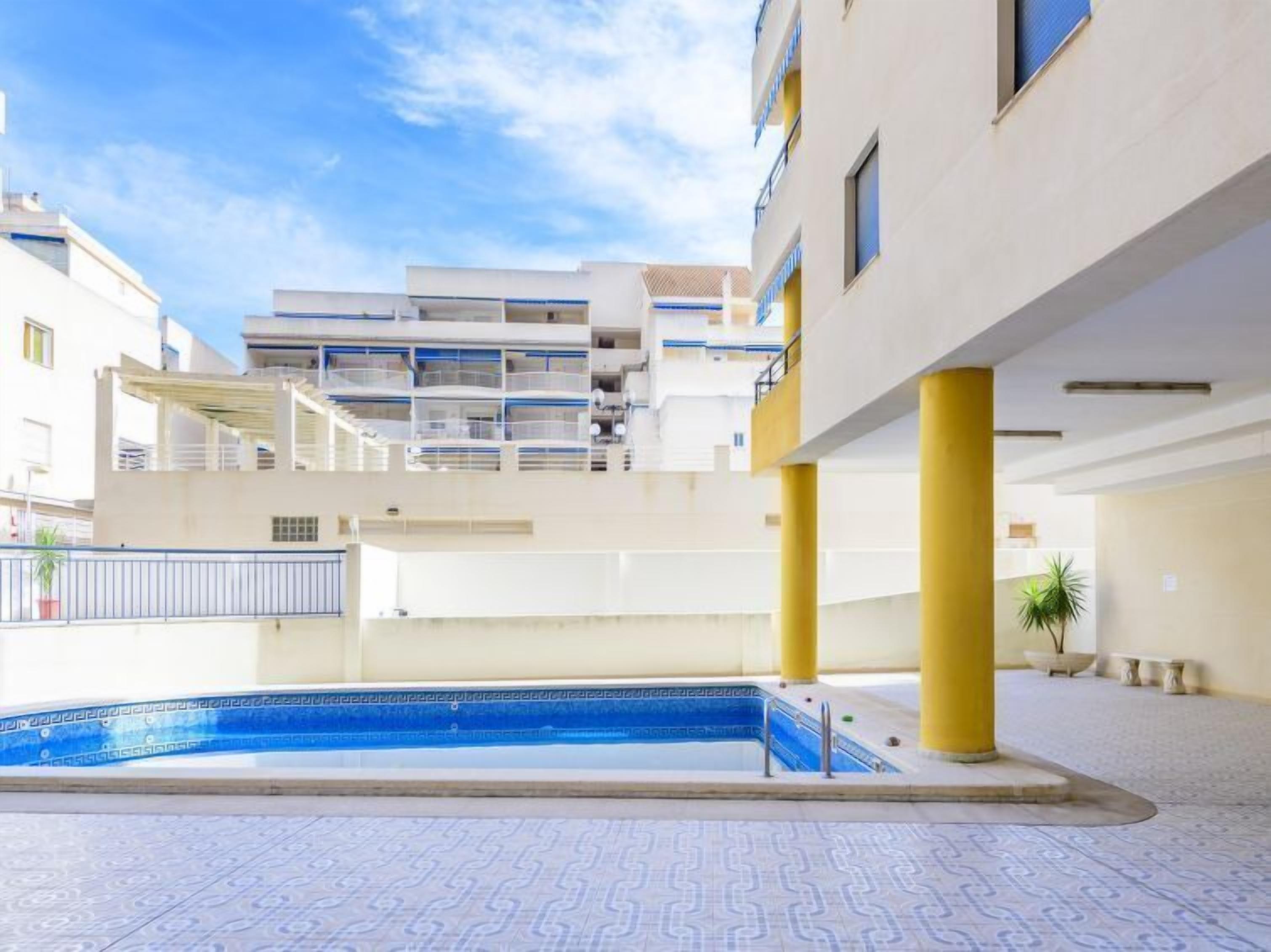 Un edificio moderno con piscina, balconi e cielo sereno.