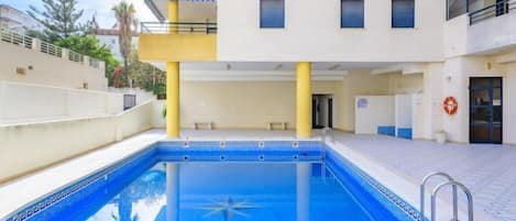 En swimmingpool med stjernemønster, omgivet af en bygning med altaner og vinduer.
