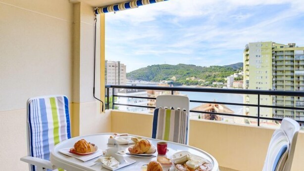 A balcony with a table set for breakfast, overlooking a cityscape and a body of water. - Torre del Rey by Interhome (Oropesa del Mar)