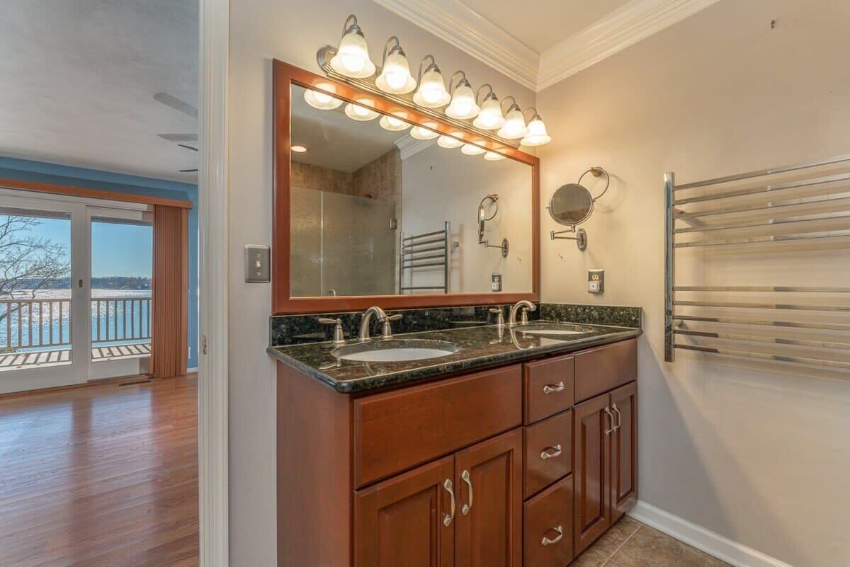 A bathroom with a double sink vanity, a large mirror, and a towel rack.