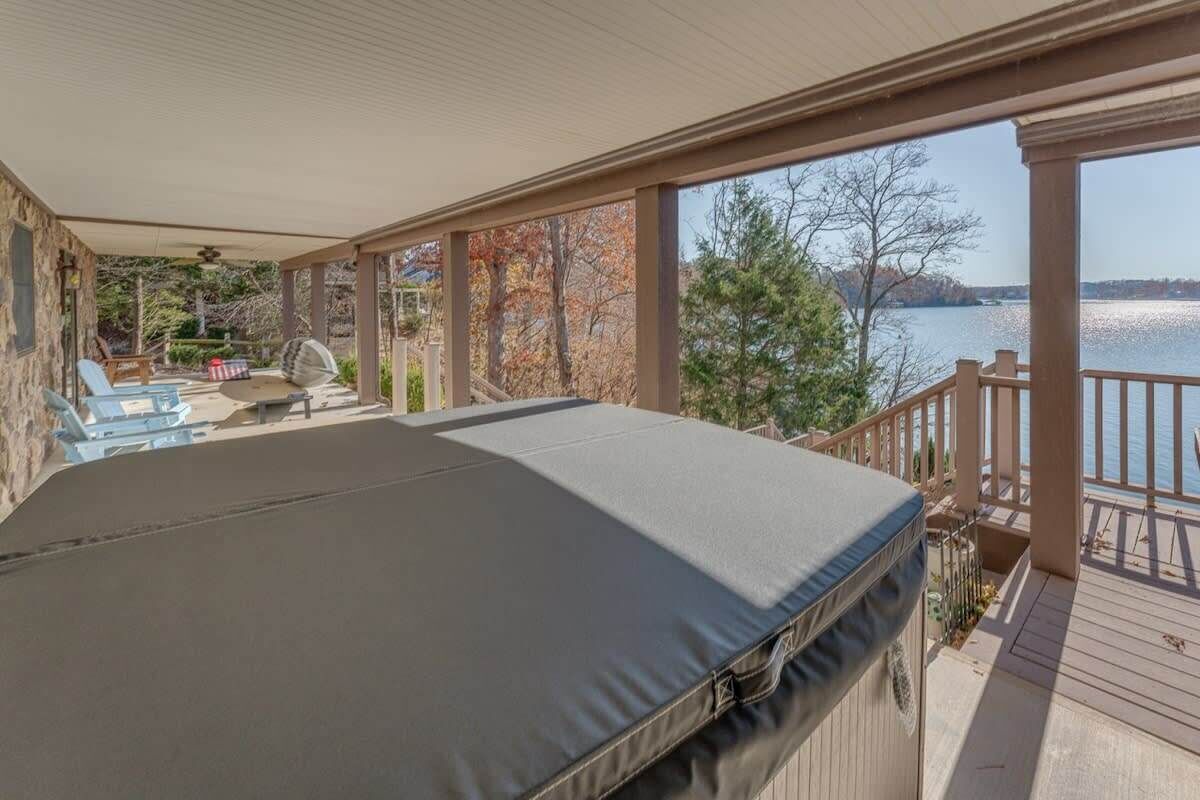 Une terrasse extérieure couverte, dotée d’un canapé et de fauteuils, qui offre une vue sur un lac.