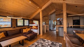 A spacious living area with a fireplace, wooden furniture, and large windows.