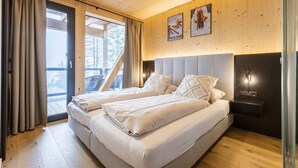 Une chambre avec deux lits, des murs en bois, un balcon et une table de chevet avec une lampe.