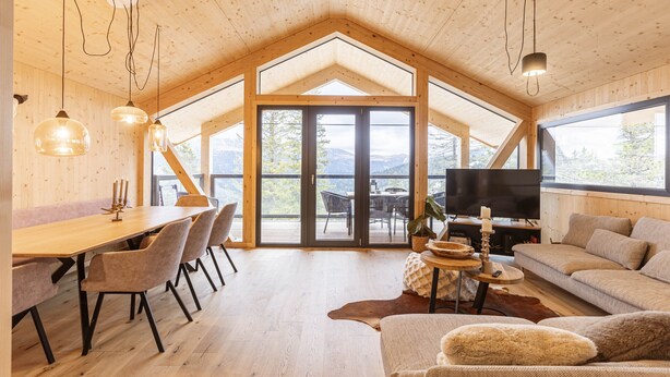Un intérieur chaleureux en bois, avec un coin repas, un canapé et un téléviseur.