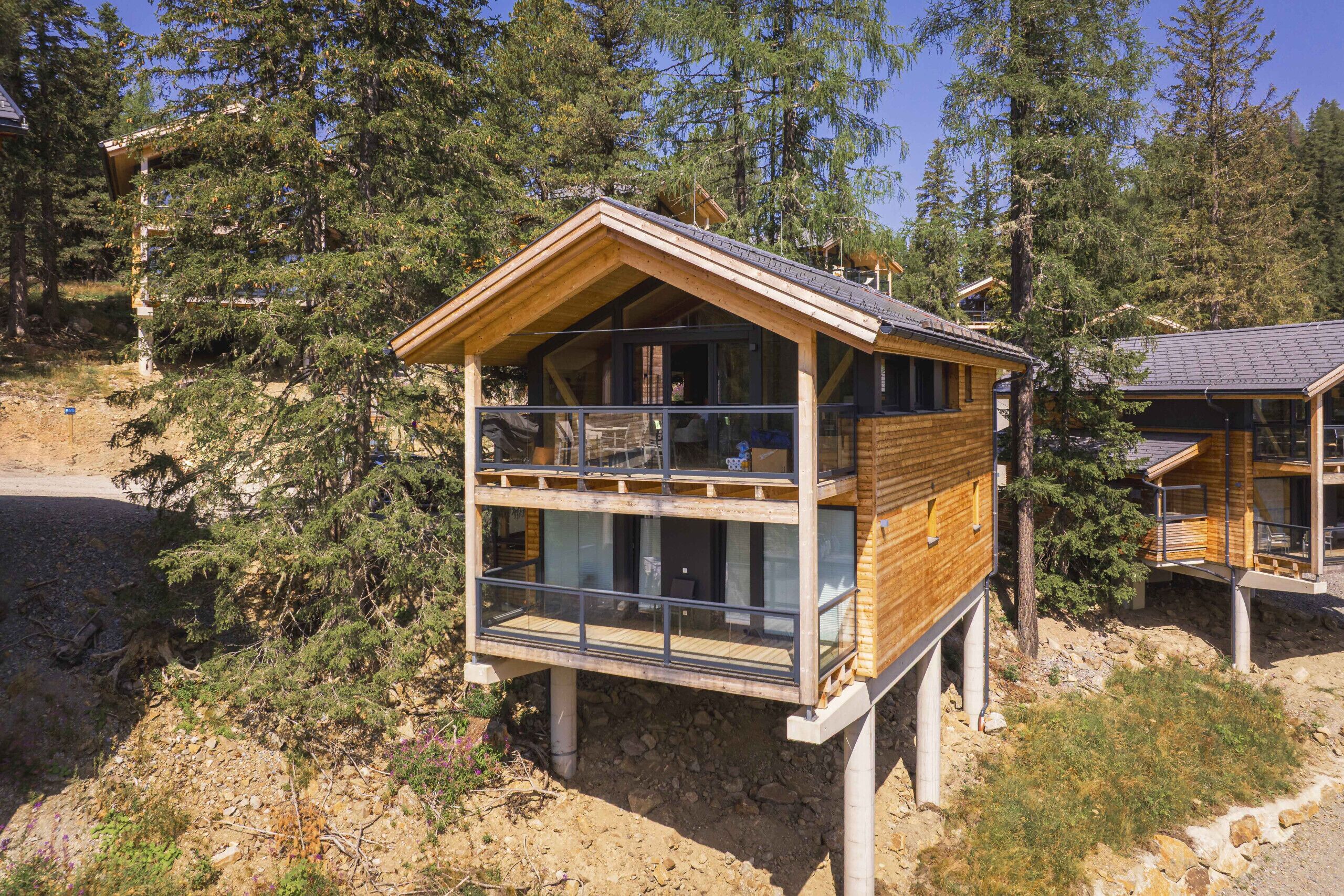 Une cabane en bois dotée d’un balcon, entourée d’arbres.