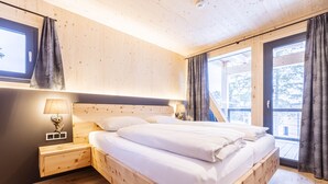 Een houten slaapkamer met een bed, nachtkastjes en een raam met gordijnen.