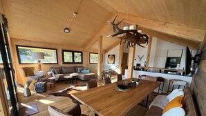 Un intérieur spacieux en bois, comprenant un coin repas, des canapés et une cuisine.