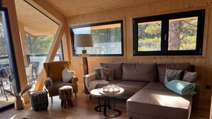 L’intérieur d’un chalet accueillant, avec un canapé, un fauteuil et une table ronde.