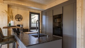 Una cocina moderna con encimera de granito, electrodomésticos de acero inoxidable y techo de madera.