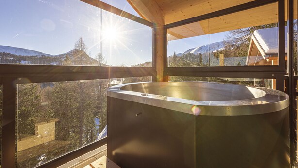 Una cabaña de madera moderna con un ventanal grande y un jacuzzi.