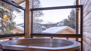 Eine Holzhütte mit großem Fenster und Whirlpool.