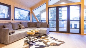 Un interior moderno con un sofá grande, un tapiz de cuero de vaca y ventanas amplias que ofrecen vistas al exterior.