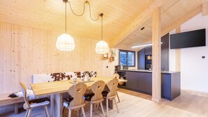 Un interior de madera con comedor, cocina y un televisor grande en la pared.