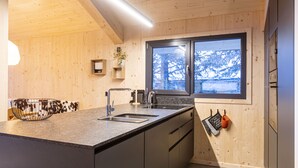 Una cocina moderna con paredes de madera, un ventanal grande y un lavamanos empotrado.