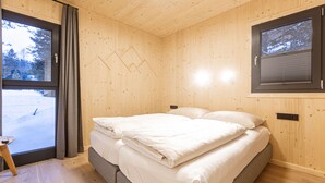 Un dormitorio con cama, ventana con cortinas y vistas a un paisaje nevado.