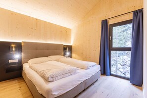Une chambre à coucher avec un grand lit, des murs en bois et une fenêtre avec des rideaux.