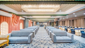 Un vaste hall doté de rangées de sièges, d’un tapis à motifs et d’un plafond décoratif.
