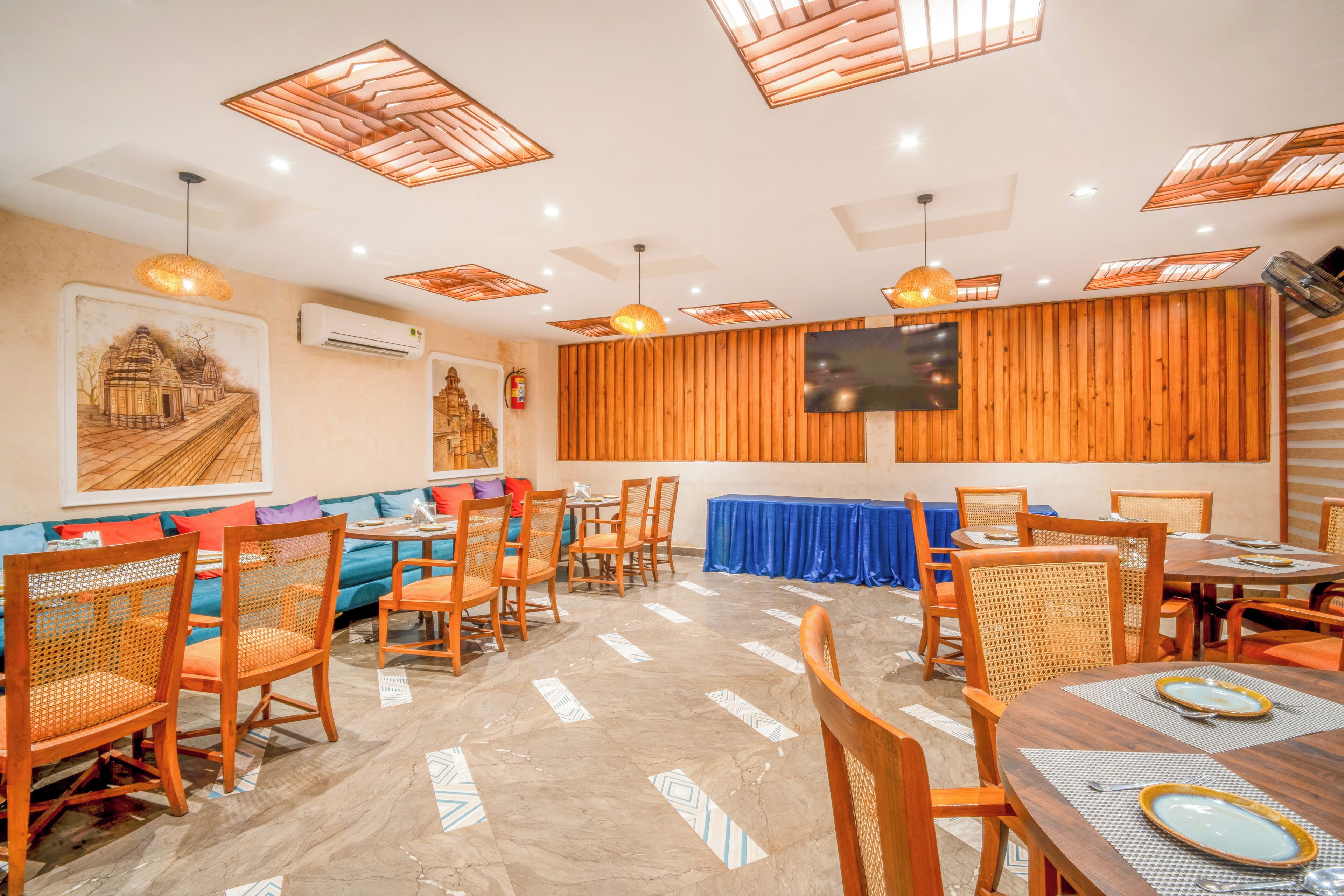 A restaurant with wooden panel walls, a blue tablecloth-covered table, and wicker chairs.