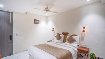 A bedroom with a bed, bedside tables, a nightstand, a ceiling fan, and wall-mounted lights.