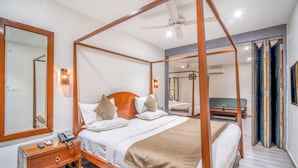 Un lit à baldaquin avec un cadre en bois, une table de chevet avec un téléphone et un miroir fixé au mur.