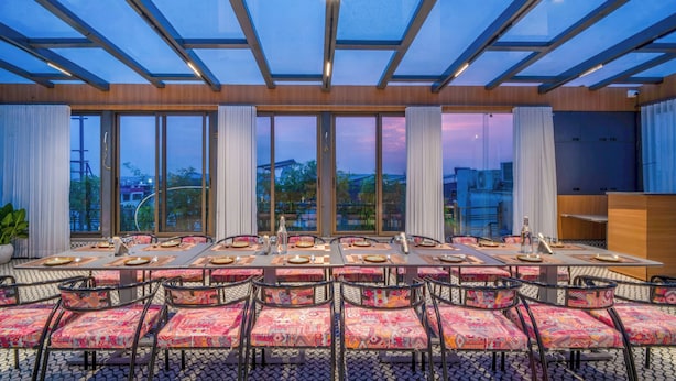 Un espace repas avec une longue table, de nombreuses chaises et un plafond en verre.