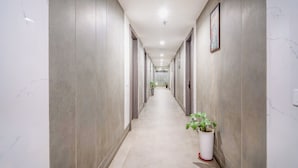 Un long couloir étroit, doté d’un sol et de murs en marbre, et bordé de portes de part et d’autre.