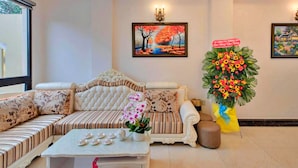 A hotel lobby with a large sofa set, a coffee table with teapots, and a floral arrangement. - HANZ Gia Hoang Hotel Dalat (Cam Ly - Da Lat)