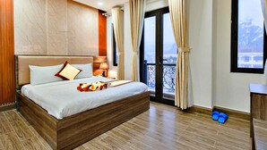 A hotel room with a large bed, a balcony with a view, and a wooden floor. - HANZ Gia Hoang Hotel Dalat (Cam Ly - Da Lat)