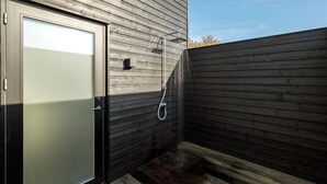 Un petit espace extérieur doté d’une porte en bois et d’une douche.