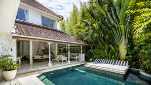 Une maison avec une piscine, un patio couvert et une végétation luxuriante.