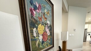 Un interior moderno con un cuadro grande de flores, un banco de madera y una escultura con forma de estrella.