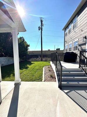 A covered outdoor area with a concrete floor, a metal railing, and a grassy lawn. - New 4BR Nephi, UT Home - 12 Beds, Game Garage, RV Pad, Near Mt. Nebo & I-15 (Nephi)