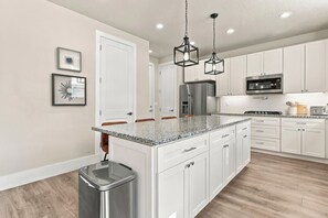 A modern kitchen with white cabinetry, granite countertops, stainless steel appliances, and pendant lighting. - New 4BR Nephi, UT Home - 12 Beds, Game Garage, RV Pad, Near Mt. Nebo & I-15 (Nephi)
