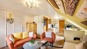 A cozy living room with a sofa, armchair, and coffee table, a kitchen in the background, and a wooden ceiling. - Apartment 'Ferienwohnung Lucke' with Mountain View, Private Terrace and Wi-Fi (Oybin-Luftkurort Lückendorf)