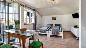 A room with a bed, a table, a chair, a TV, and a window. - Studio Apartment 'Appartement  Braun 3' with Mountain View, Balcony and Wi-Fi (Bolsterlang)